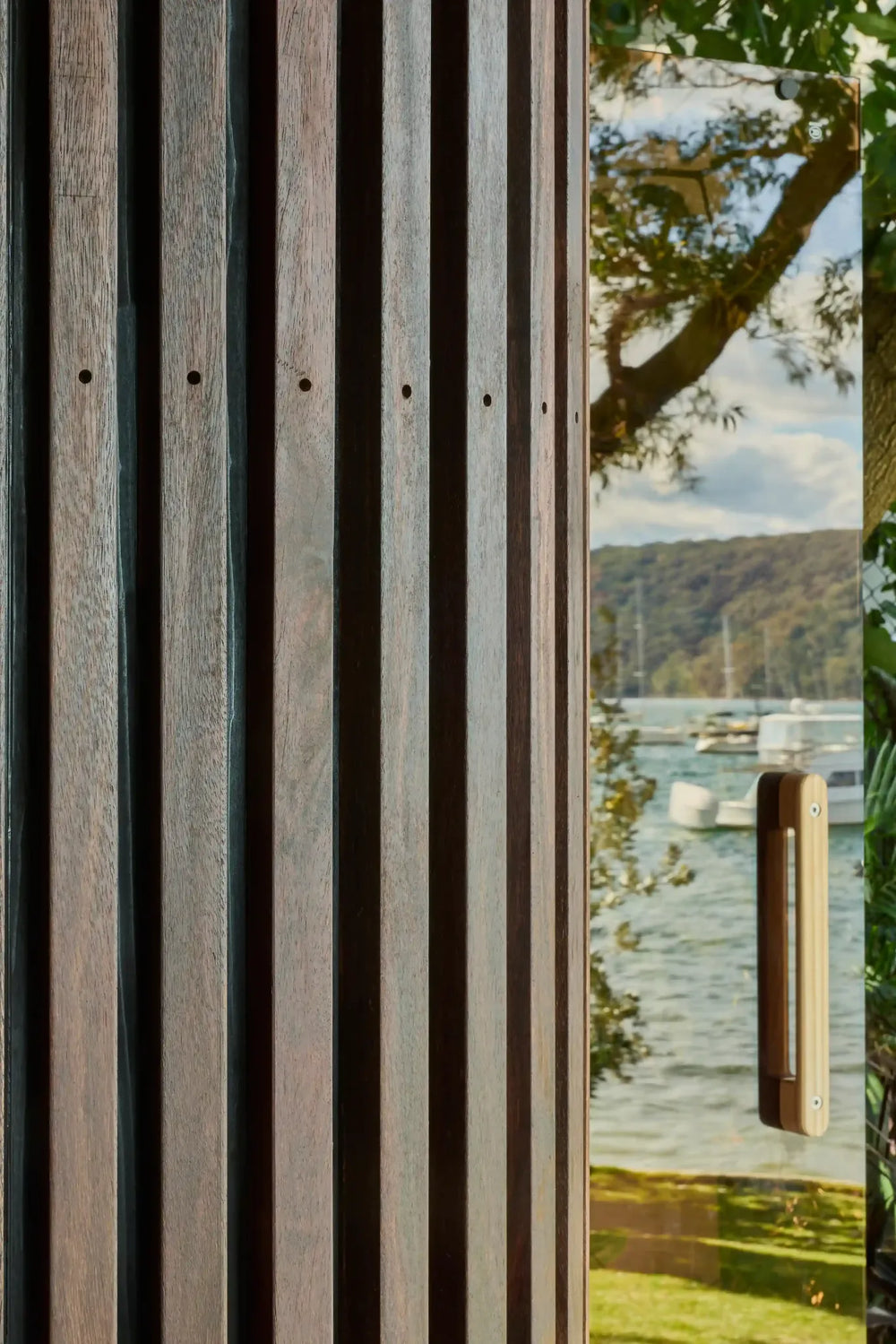 Close-up of Elata’s timber battens and glass door beside the waterfront