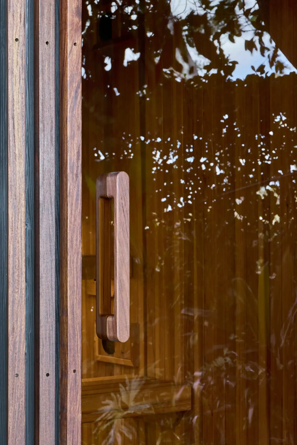 Timber door handle and foliage reflections on Elata’s tinted glass